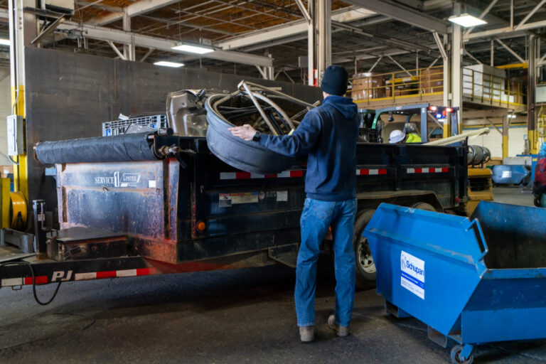 An individual unloading scrap metal from a bin.