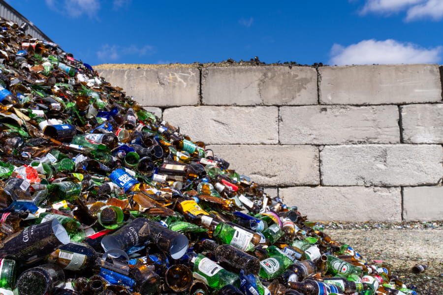 A pile of bottles and cans in front of a brick wall.